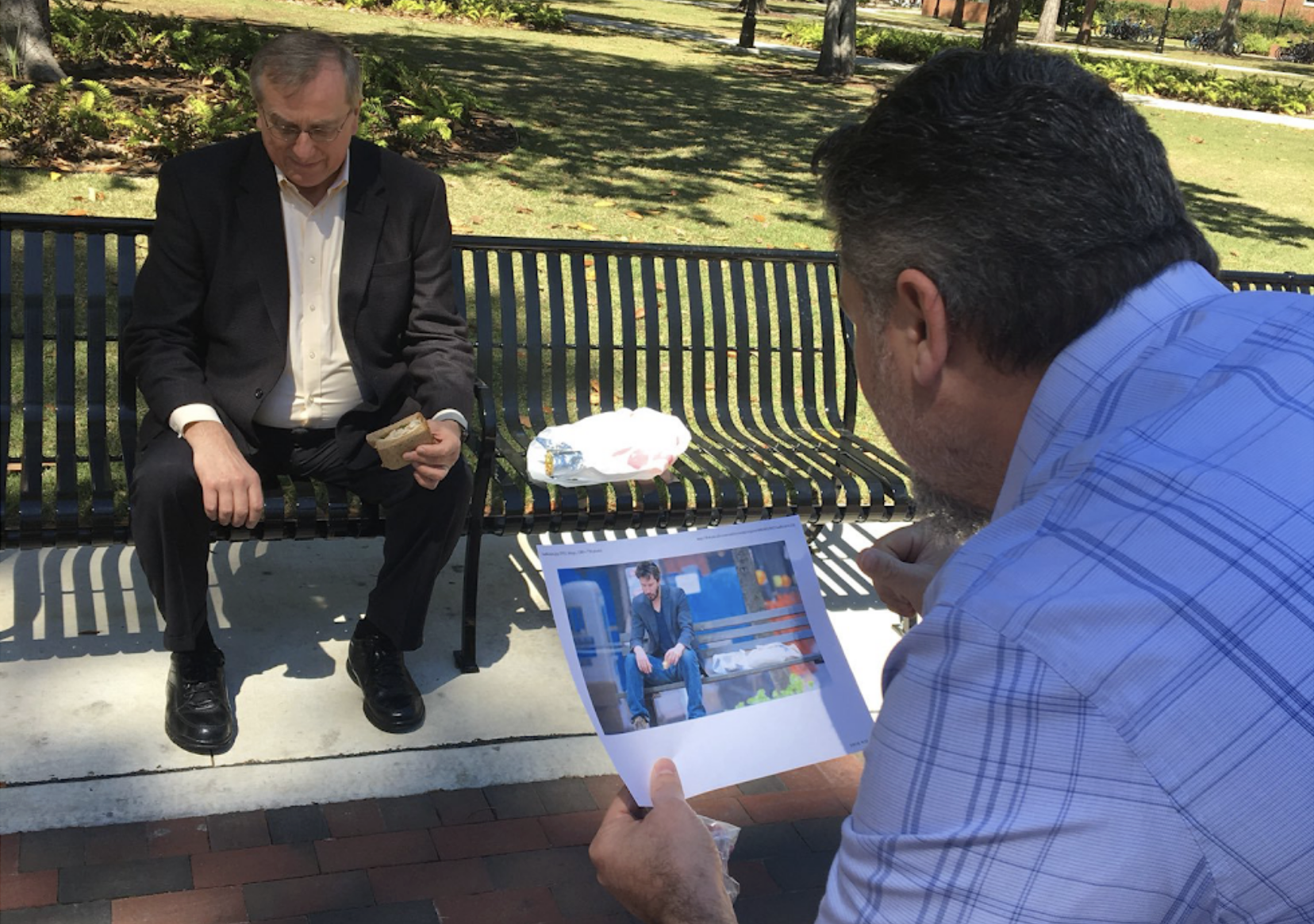 UF President sitting on a bench eating a sandwich, being shown the Sad Keanu meme
