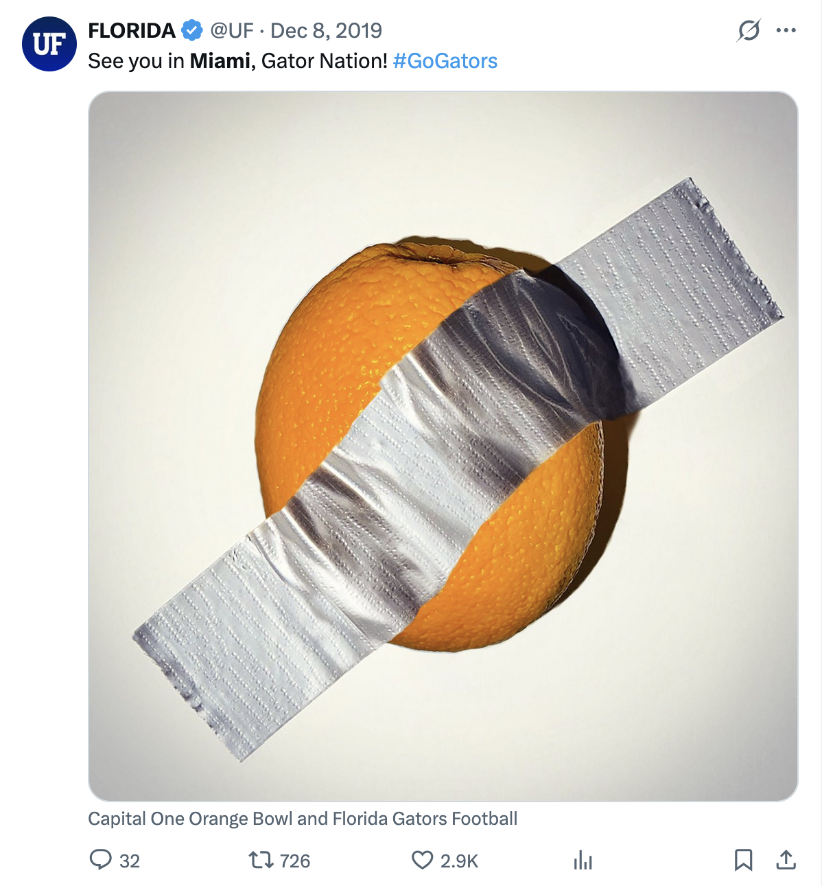 Tweet from @UF on December 8, 2019 showing an orange duct-taped to a wall with the caption 'See you in Miami, Gator Nation!' — a playful reference to Maurizio Cattelan's art piece 'Comedian'